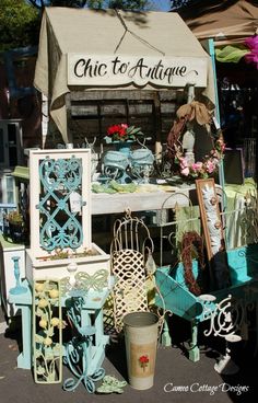 a table with chairs and other items on display at an outdoor flea market in front of a tent