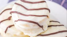 three pieces of chocolate covered doughnuts on a plate with white frosting and drizzled