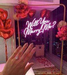 a woman's hand is in front of a neon sign that says, well you marry me?