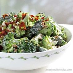 a white bowl filled with broccoli covered in bacon next to a glass bottle