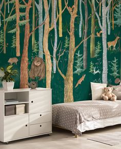 a child's bedroom decorated in green and white with trees, deers, and bears on the wall