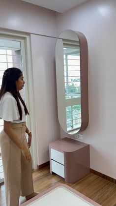 a woman standing in front of a large mirror