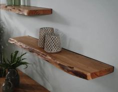 two wooden shelves on the wall with vases next to them and a plant in a pot