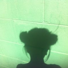 the shadow of a woman's head against a wall with a hat on it