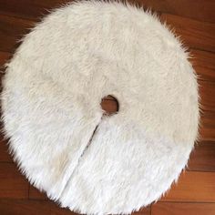 a white round rug on top of a wooden floor with a hole in the middle