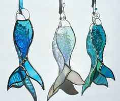 three pieces of stained glass are hanging from hooks on a hook, one is blue and the other is green