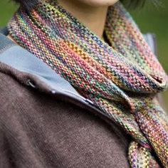 a woman with short hair wearing a multicolored knitted scarf on her neck