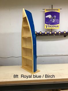 a blue and yellow boat shaped book shelf on top of a wooden table next to a sign