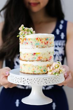 a woman holding a cake with sprinkles on it