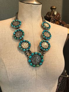 Women's Navajo Handmade Statement Necklace Set The Niko Turquoise + Vintage Coin Necklace Set Product Details Sterling silver and turquoise Authentic antique coins Rope trim and sterling drop accents Handmade 7mm seamed pearls 24" long Includes matching earrings Stamped sterling and signed by Navajo artist Colors: Green and blue Shop more from our necklace collection, here. Artisan Turquoise Medallion Jewelry, Traditional Silver Turquoise Concho Necklace, Traditional Silver Turquoise Necklace With Concho, Traditional Turquoise Jewelry With Concho, Traditional Turquoise Necklace With Concho, Turquoise Concho Bohemian Necklace, Bohemian Jewelry With Coin Pendant For Collectible, Traditional Turquoise Concho Necklace, Traditional Turquoise Concho Jewelry