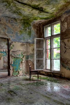 an old room with peeling paint and a chair