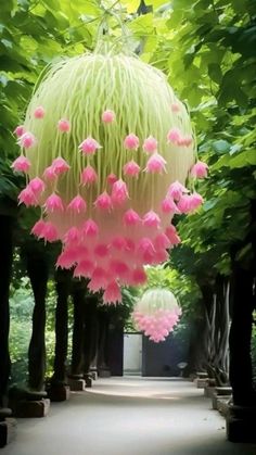 pink flowers are hanging from the ceiling in an outdoor area with trees and walkways