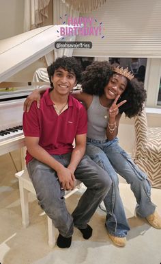 a man and woman sitting on a bench in front of a piano smiling at the camera