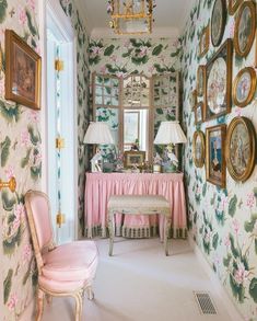 a pink chair sitting in front of a mirror next to a wall with pictures on it