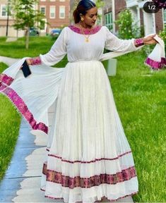 Ethiopian and Eritrean traditional dress, a Habesha Kemis. This particular dress features white cotton fabric with detailed embroidery, highlighting the neckline, sleeves, and hem in a beautiful purple and gold pattern. The dress is elegant and flows gracefully, often worn during special occasions and cultural celebrations in Ethiopia.             100%cotton Eritrean Dress, Ethiopian Clothing, Habesha Dress, Ethiopian Traditional Dress, Ethiopian Dress, Habesha Kemis, Traditional Dress, Dress Elegant, Wedding Men