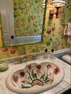 a bathroom sink sitting under a mirror next to a wall mounted faucet with flowers on it