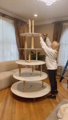 a woman is working on some shelves in the living room