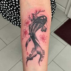 a woman with a tattoo on her arm has a fish and cherry blossoms in it