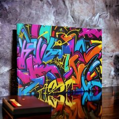 a laptop computer sitting on top of a wooden table next to a graffiti covered wall