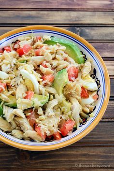 a bowl filled with pasta salad on top of a wooden table