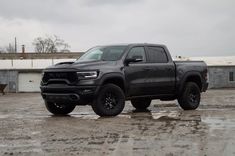 a black truck parked in a parking lot next to a building on a cloudy day