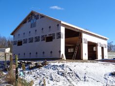 a house under construction in the winter with snow on the ground and ladder up to it