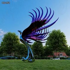 a large metal bird sculpture sitting on top of a lush green field