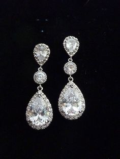 two pairs of diamond earrings on a black background