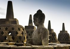 a stone buddha statue sitting in front of some buildings