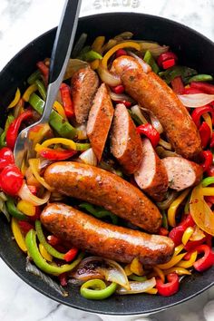 sausages and peppers in a skillet with tongs