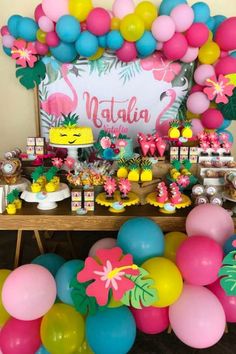 a table topped with lots of balloons and desserts next to a sign that says nattia