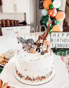 a birthday cake decorated with animals and balloons