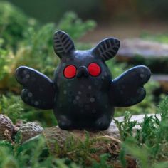 a black toy with red eyes sitting in the grass