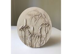 a white ceramic plate with flowers and trees on the front, sitting on a table