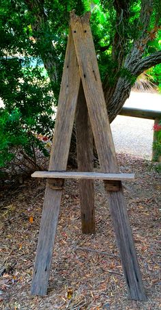 a wooden bench sitting in the middle of a forest next to a lush green tree