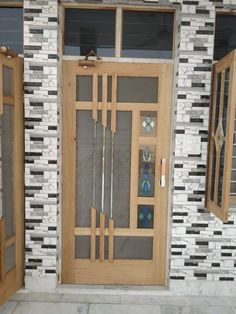 a wooden door with glass panels on the side of a brick wall next to two windows