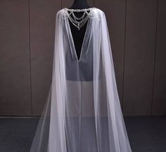 a white wedding veil with beaded details on the neckline and back, draped over a mannequin