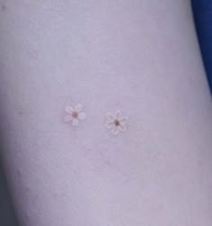 two small white flowers on the side of a woman's thigh