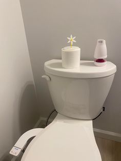 a white toilet with the lid up and a yellow flower on it's tank