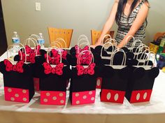 a woman standing next to a table with minnie mouse treat bags on top of it