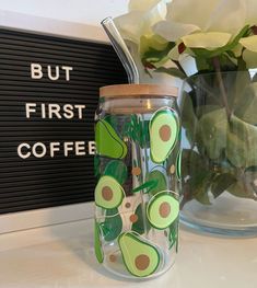 an avocado painted mason jar next to a vase with flowers