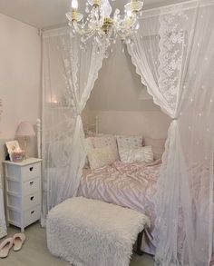 a bedroom with a white canopy bed and chandelier