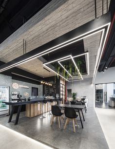 an open concept kitchen and dining area in a modern building with concrete floors, exposed lighting and black chairs