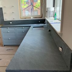 a kitchen counter top being installed in front of a window with no curtains on it