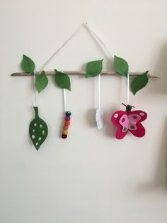 the wall is decorated with green leaves and pink butterfly decorations hanging from it's hooks