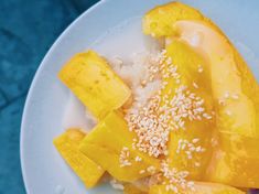 a white plate topped with rice and mangos on top of a blue tablecloth