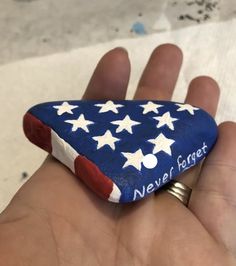 a hand holding a rock with the words never forget on it and stars painted on it