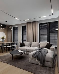 a living room filled with lots of furniture and windows covered in draping next to a dining table