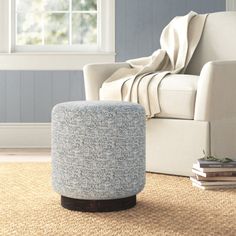 a living room with a chair, ottoman and rug on the floor in front of a window