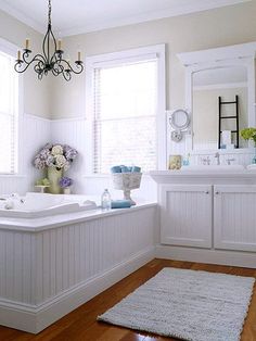 a white bathroom with wood floors and chandelier